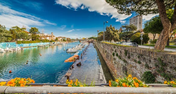 Photo of Bridge on Rimini canal port with boats, modern buildings and old houses.