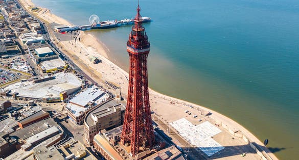 Photo of aerial view of the Blackpool Tower with the Central pier in the background located in Blackpool, UK.