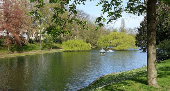 photo of view of Ixelles pond in October. Church reflection in water. Sunny autumn afternoon, Ixelles, Belgium.