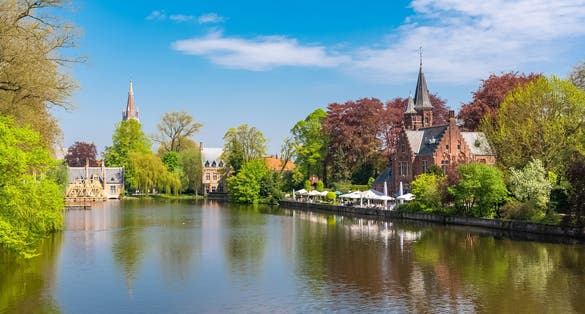 Bruges in Belgium, beautiful typical houses on the canal, and a church in background