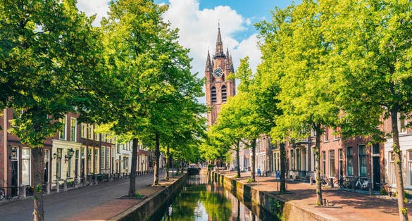 photo of Oude Delft canal and leaning tower of Gothic Protestant Oude Kerk church, Delft, Holland, Netherlands.