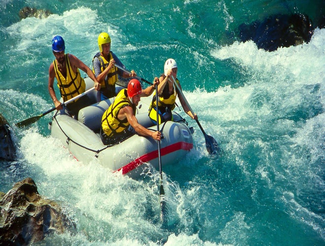 Group of people white-water rafting through rapids on the Soca River in Slovenia..jpg