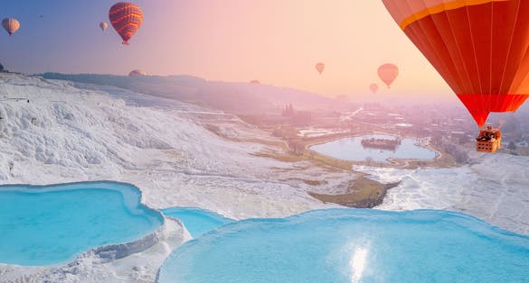 Photo of hot air balloon flying Travertine pool and terraces sunset, Denizli, Turkey.