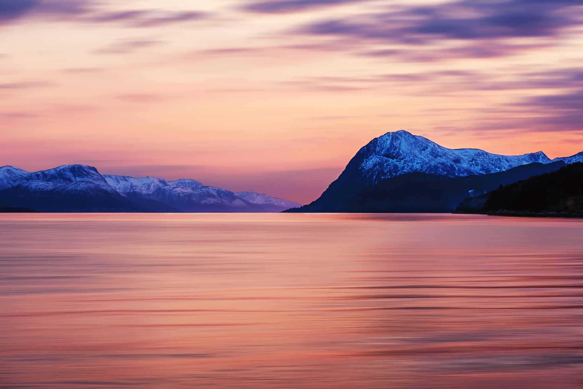photo of view of Molde, Norway. Beautiful fjord in Norway at sunset. View of the mountains in Molde, Norway in the evening. Fjord with sea in summer, cloudy motion blurred sky and waves