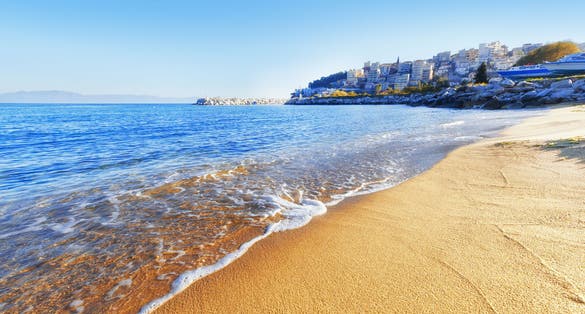 Photo of yellow sand beach against Kavala city in background. Kavala is famous summer greek resort town.