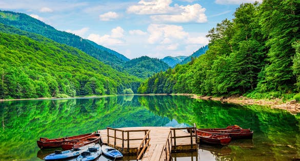Photo of wooden boats and kayaks near pier on Biogradskoe lake in Montenegro.