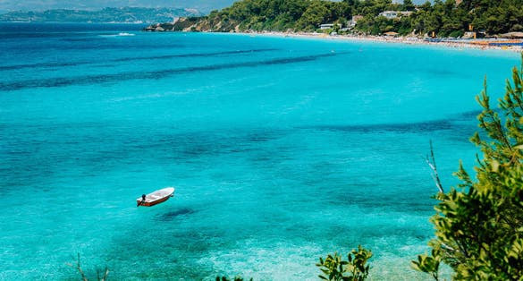 Photo of white boat in crystal clear blue sea water. Spectacular Platis Gialos and Makris Gialos Beach, Argostoli, on Kefalonia island.