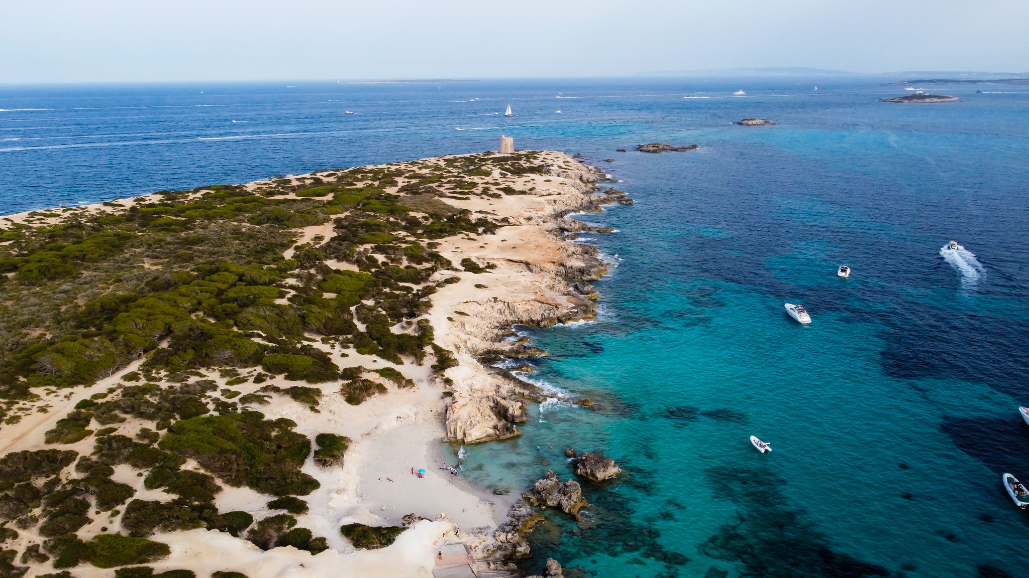 photo of an aerial view of Punta de sa Torre de Ses Portes, a sandy point in the south of Ibiza island in Spain with a medieval round defensive tower.