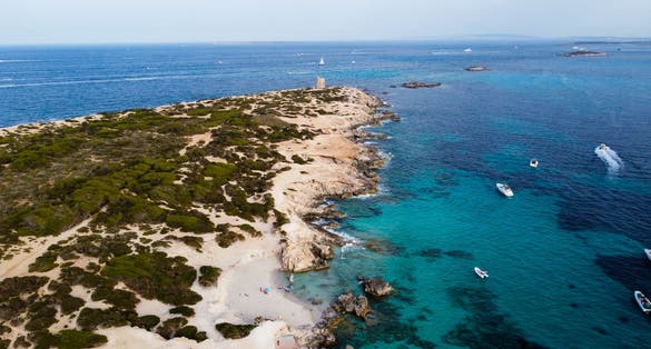 photo of an aerial view of Punta de sa Torre de Ses Portes, a sandy point in the south of Ibiza island in Spain with a medieval round defensive tower.