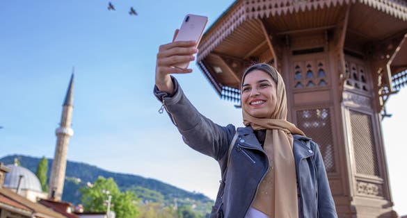 Muslim woman with hijab is taking selfie in front of the Sebilj in Sarajevo.