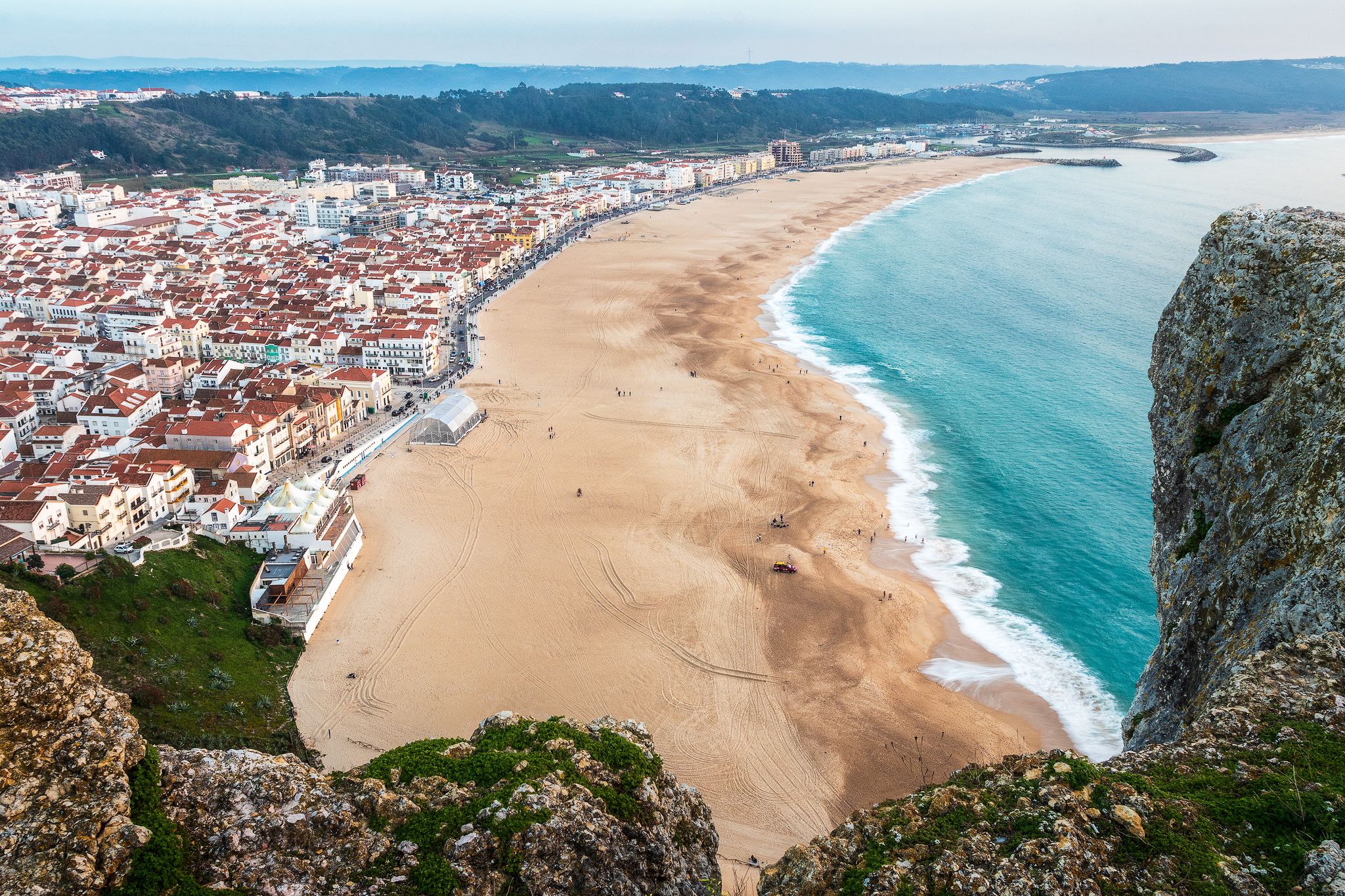 Nazaré beach seen from above, from the viewpoint of the Sí­tio, with rocks in foreground.