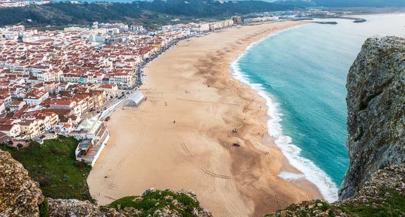 Nazaré beach seen from above, from the viewpoint of the Sí­tio, with rocks in foreground.
