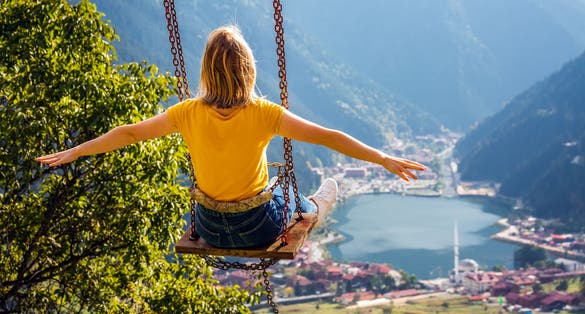 Photo of female on a swing with the view of the mountain lake Uzungol, Trabzon, Turkey.