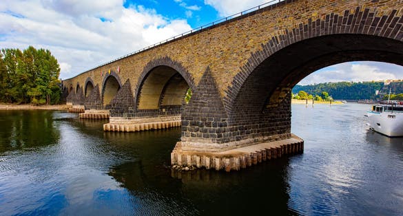 photo of view of Pleasure boat. Romantic trip to medieval Germany. Scenic Baudouin bridge over the majestic river Moselle connects the Old Town with the Lützel district. Koblenz. Cloudy warm autumn day