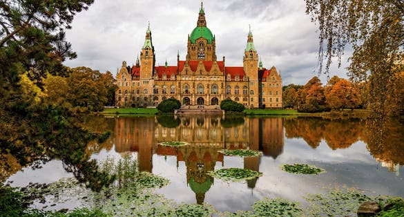 photo of view of Magnificent, castle-like building of New City Hall in Hannover, Lower Saxony, Germany., reflected in autumn park pond. It is a popular tourist attraction in Hannover