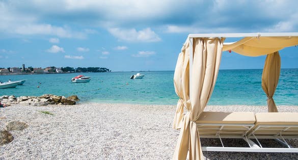 Summer view on Poreč from luxury baldachin on a pebble beach