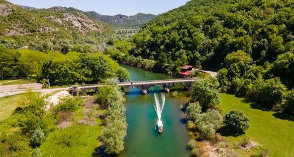 Photo of aerial view of old bridge with a boat passing under it, Rijeka, Croatia.