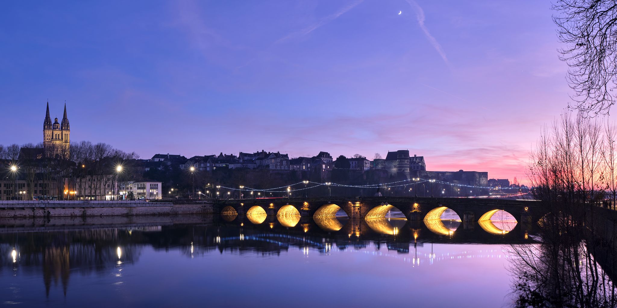 photo of  view of Skyline of Angers by night, city of France, with the cathedral, the castle, and a bridge, during the sunset with a beautiful colorfull sky