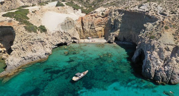 photo of view of erial drone photo of beautiful volcanic emerald paradise bay and sandy beach of Tsigrado below white rock with perlite mine, Milos island, Cyclades, Greece.