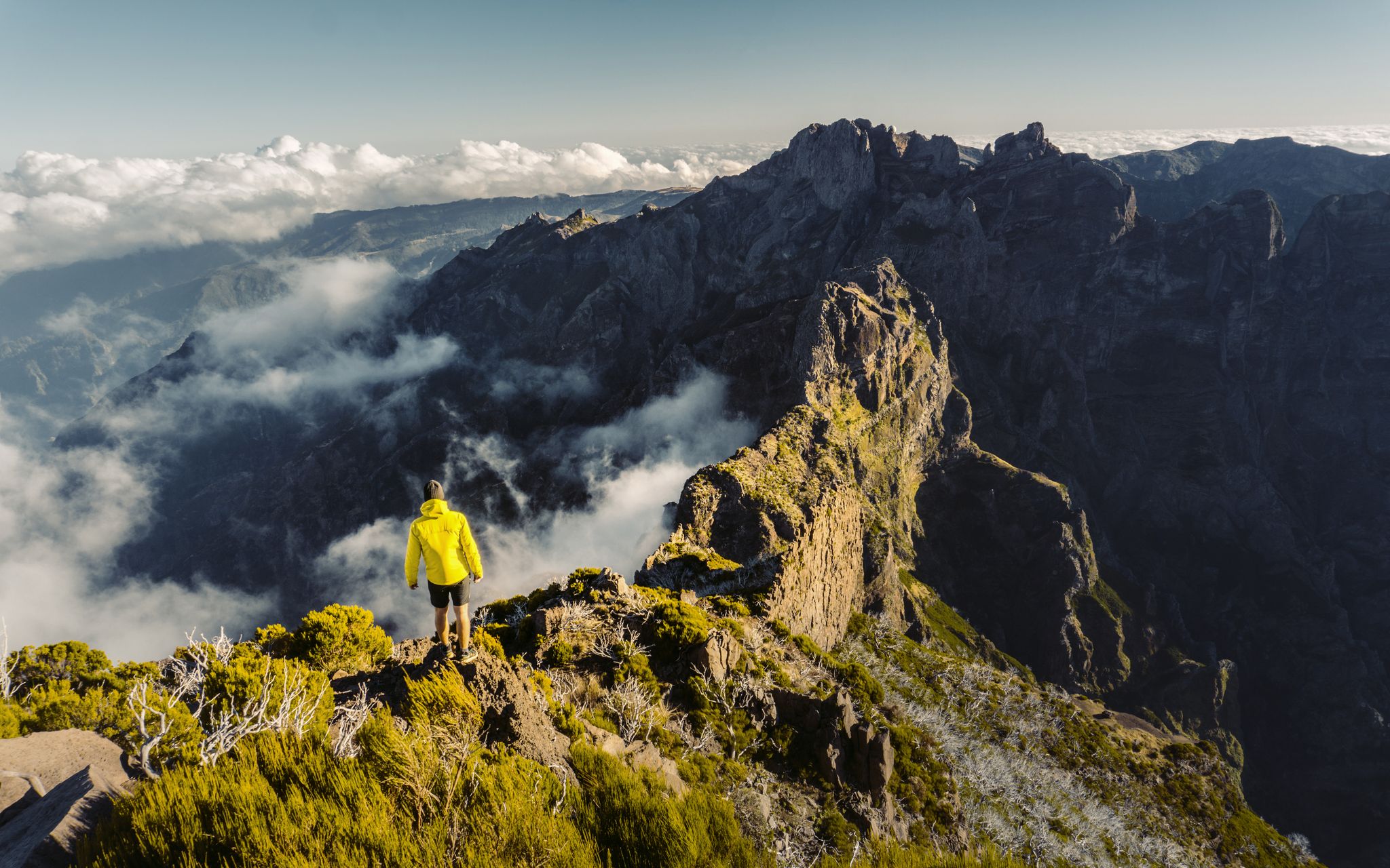 Man stands alone on the peak of rock. Beautiful moment the miracle of nature. Colorful mist in valley. Man hike. Trekking from Pico do Arieiro to Pico Ruivo, Madeira island, Portugal.