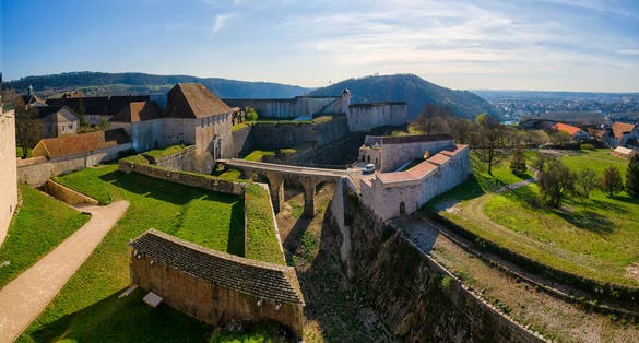 Top view of the entrance to the citadel from the city of Besancon. France. There are numerous defenses and a mountain landscape. Visible part of the city.