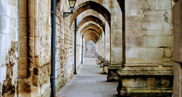 Photo of great medieval engineering, looking through the arches underneath the flying buttresses of the Winchester Cathedral, UK.