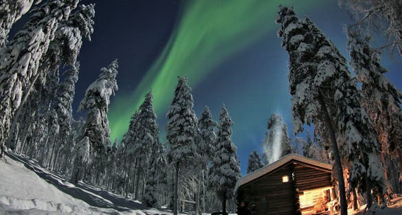 winter landscape in Lapland, snow miracle behind the polar circle in the arctic winter, hidden log cabin under moon light and aurora borealis in the PyhÃ¤-Luosto National Park near of SodankylÃ¤
