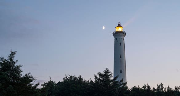 Photo of Lyngvig Lighthouse illuminated at night at the Danish West Coast, Denmark.