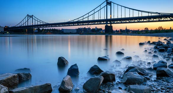 Photo of old bridge crossing the Rhine river during sunset, Krefeld, North Rhine Westphalia, Germany.