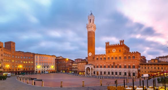 photo of mangia tower or torre del mangia towering above of the palazzo pubblico on piazza del campo in medieval city of Siena at beautiful sunrise, tuscany, Italy.