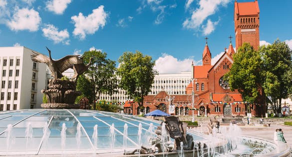 Photo of church of Saints Simon And Helen or Red Church And Fountain At Independence Square In Minsk.
