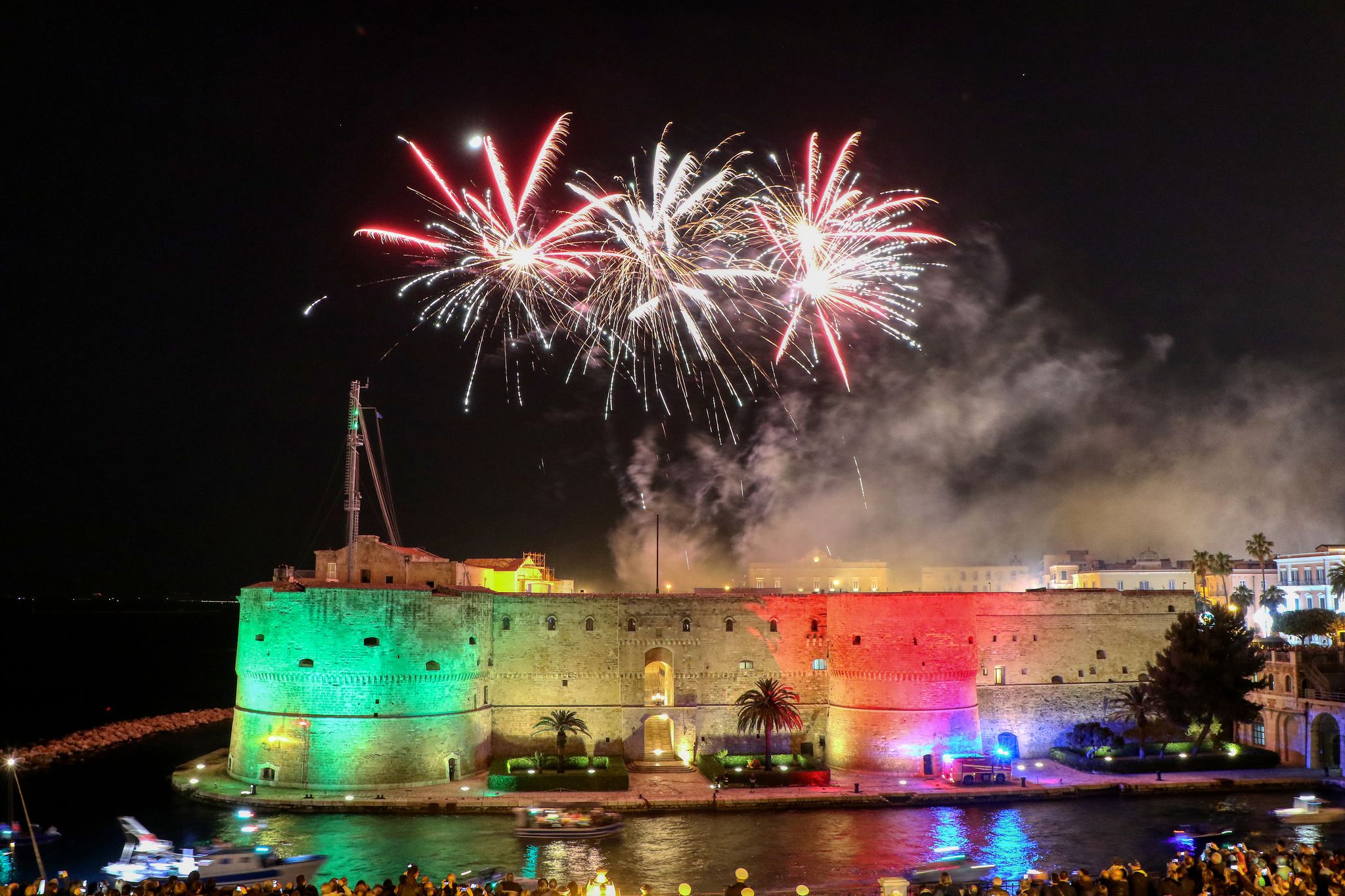 photo of Aragonese Castle (officially called the Castel Sant'Angelo) at night with fireworks on the feast of San Cataldo, Patron Saint of Taranto, Puglia, Italy.