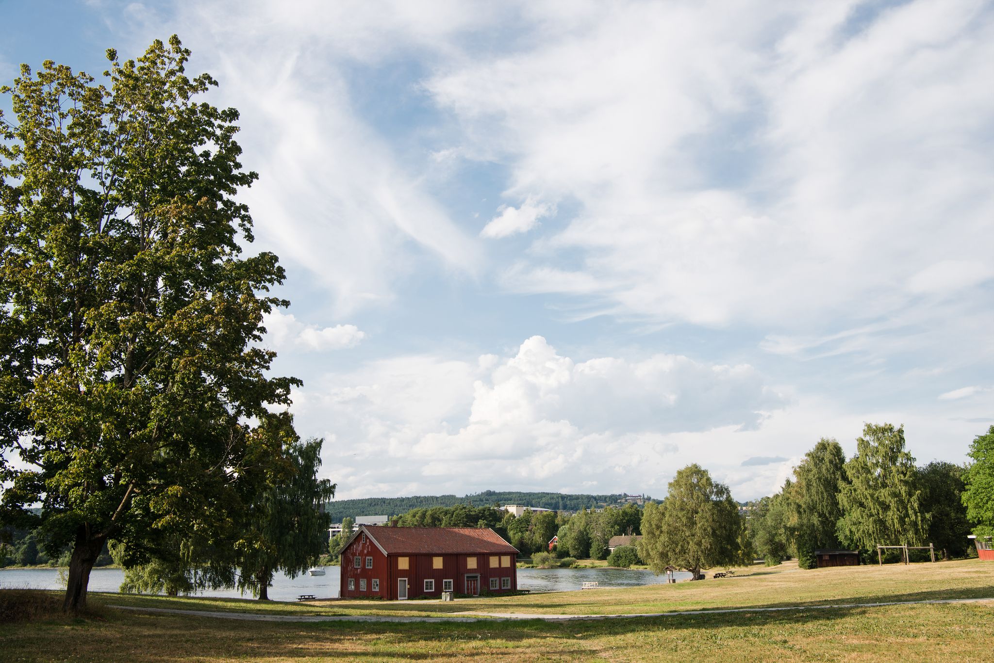 photo of view of red house near lake under cloudy sky, Hamar, Hedmark, Norway.