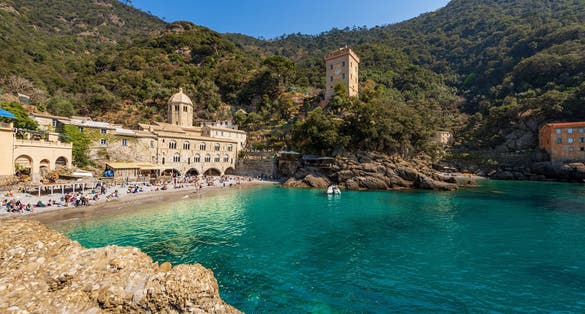 photo of view of Beach with tourists in San Fruttuoso bay with the ancient Abbey (San Fruttuoso di Capodimonte, Italy.