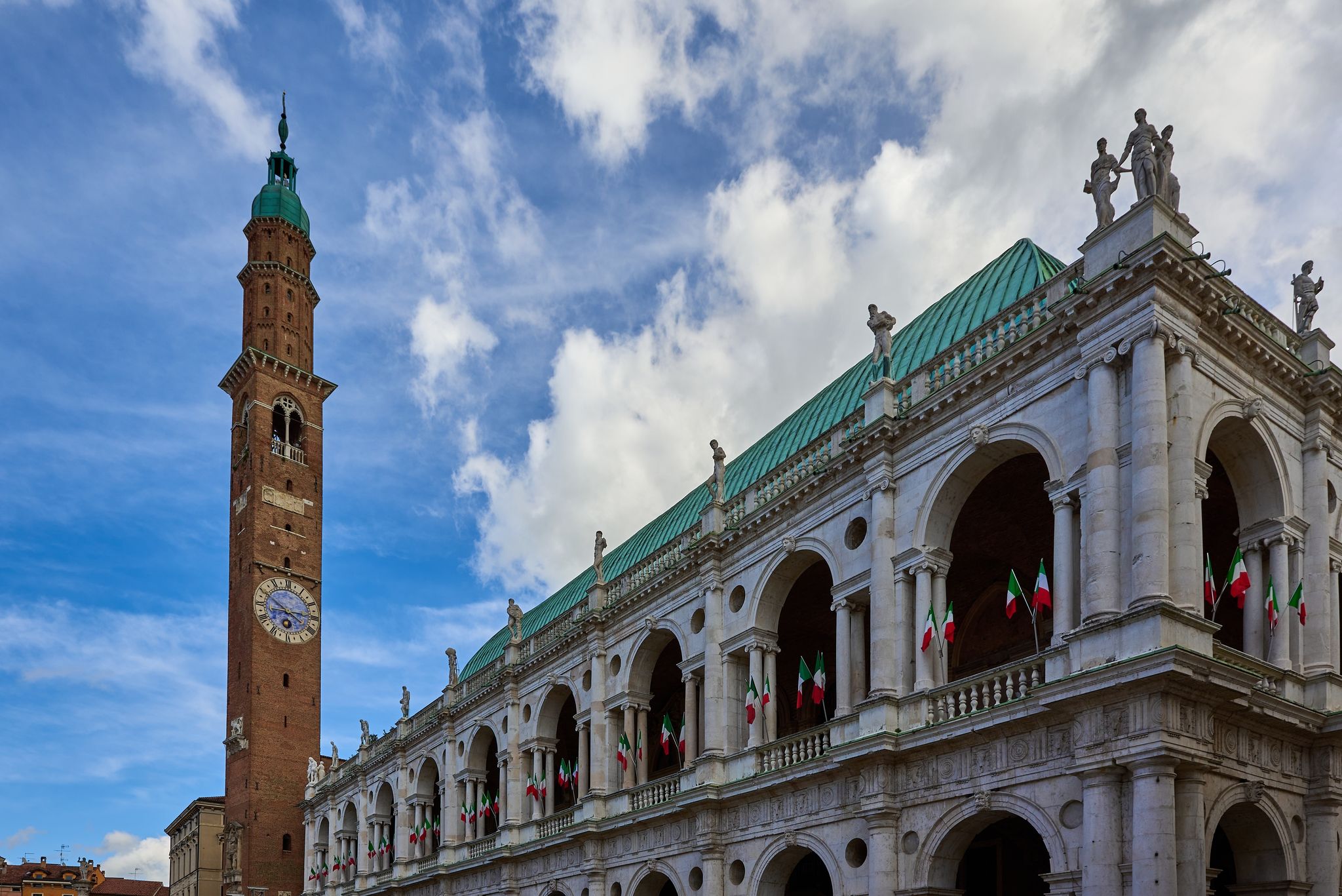 photo of View of the famous Basilica Palladiana (Palazzo della Ragione) with clock tower decked out with Italian flags located in Piazza Dei Signori in Vicenza, Veneto, Italy