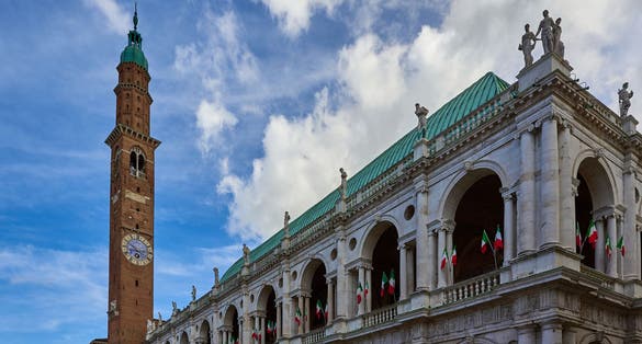 photo of View of the famous Basilica Palladiana (Palazzo della Ragione) with clock tower decked out with Italian flags located in Piazza Dei Signori in Vicenza, Veneto, Italy