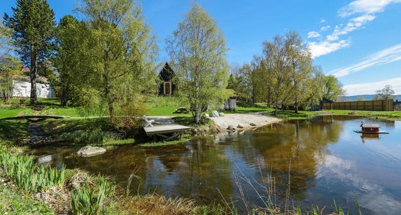 Sverresborg Trøndelag Folk Museum, open-air museum in Trondheim, Norway. Old timber house. Pond with the white bench.