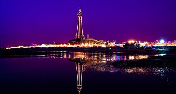 Photo of the famous Blackpool Tower illuminated at night and the beach in Blackpool, United Kingdom.