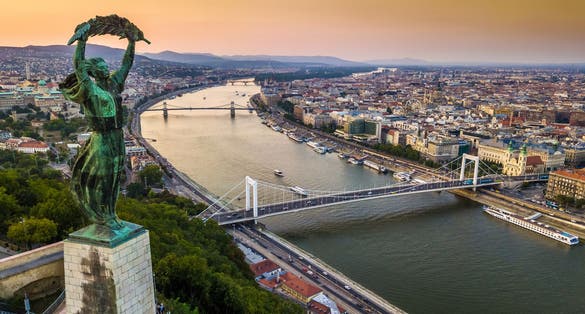 photo of Budapest, Hungary - The Hungarian Statue of Liberty at sunrise with Elisabeth Bridge and Szechenyi Chain Bridge and skyline of Budapest at background