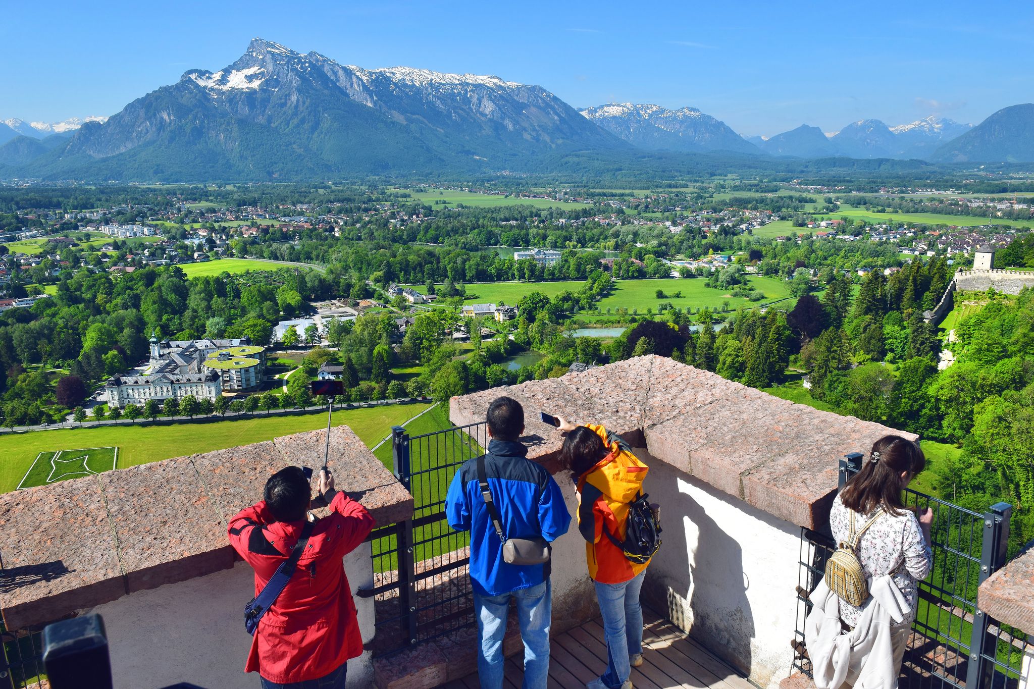 Photo of tourists take pictures the neighborhood of Salzburg from the height of the watchtower of Hohensalzburg Fortress, Salzburg, Austria.