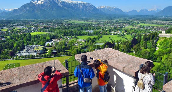 Photo of tourists take pictures the neighborhood of Salzburg from the height of the watchtower of Hohensalzburg Fortress, Salzburg, Austria.