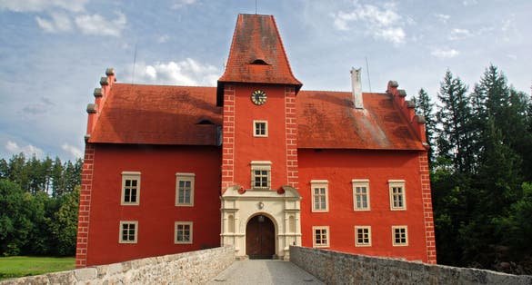 Photo of castle Cervena Lhota, red château standing at the middle of a lake on a rocky island, Czech Republic.