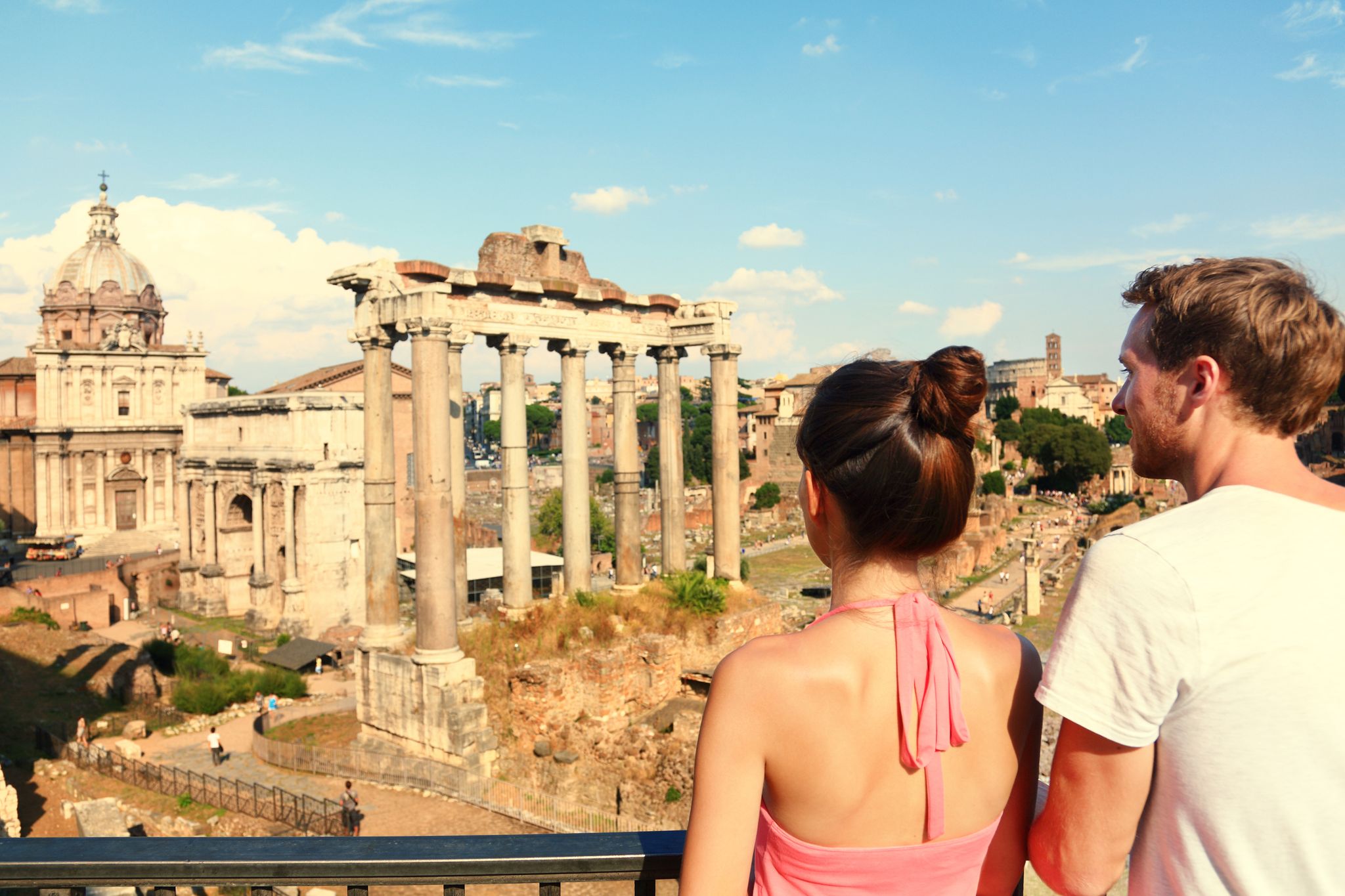 photo of Rome tourists looking at roman forum landmark in Rome. Couple sightseeing on travel vacation in Rome, Italy. Happy tourist couple, man and woman traveling on holidays in Europe.