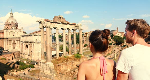 photo of Rome tourists looking at roman forum landmark in Rome. Couple sightseeing on travel vacation in Rome, Italy. Happy tourist couple, man and woman traveling on holidays in Europe.