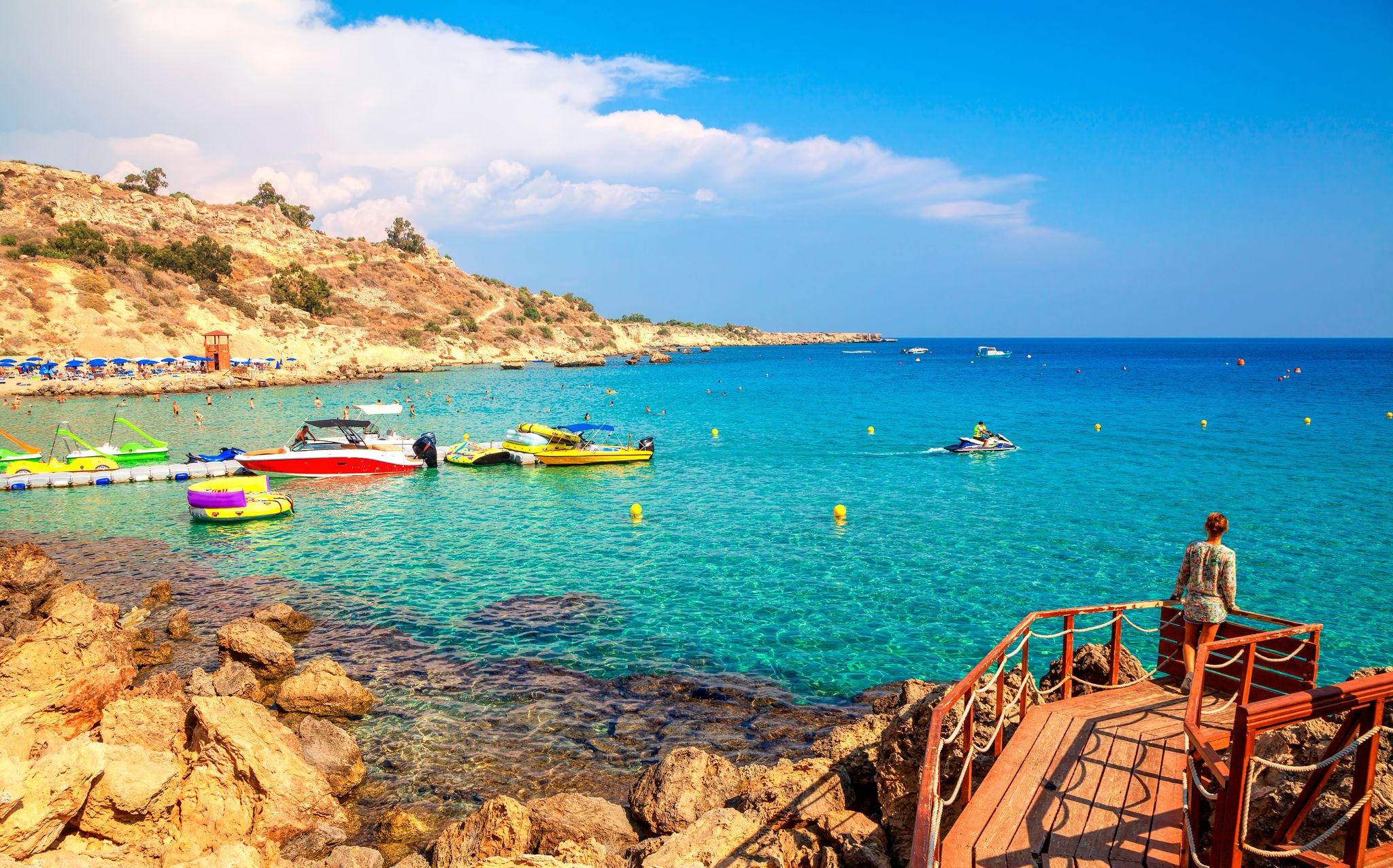 Photo of tourist on wooden pier on Konnos Beach of Cyprus island. Cape Greko natural park. Beautiful sand beach between Aiya Napa and Protaras