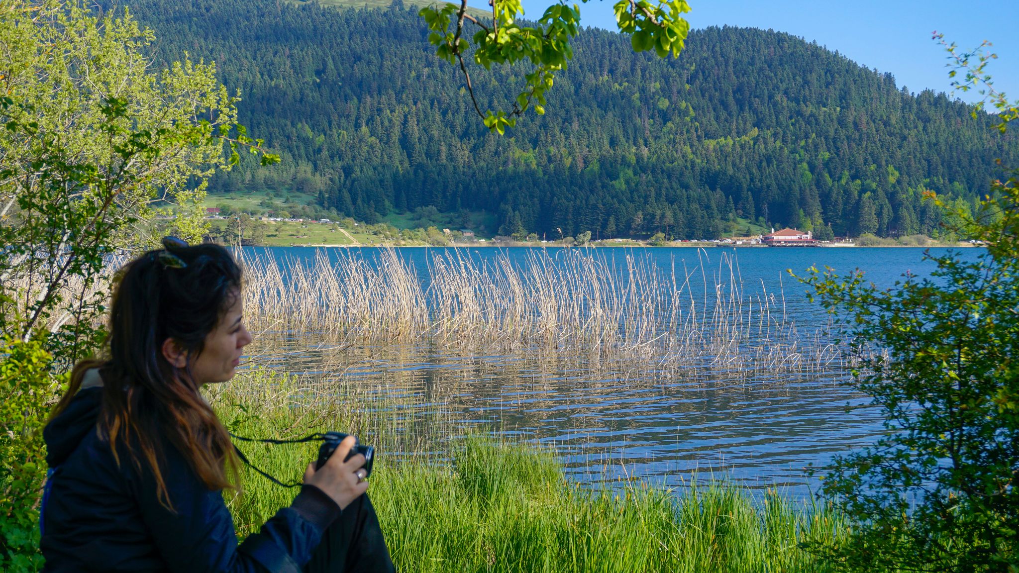 photo of young woman photographer sitting and taking photo on the edge of an attractive lake. Abant Gol (Paradise Lake), Bolu ,Turkey.