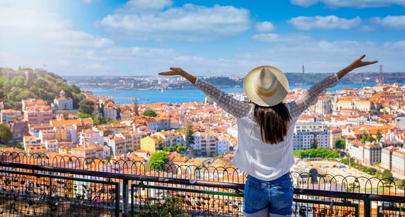 Photo of a happy tourist woman overlooks the colorful old town Alfama of Lisbon city, Portugal.