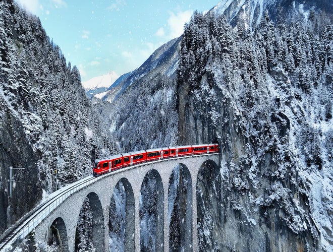 Glacier Express train crossing a snowy viaduct through the Swiss Alps in winter..jpg