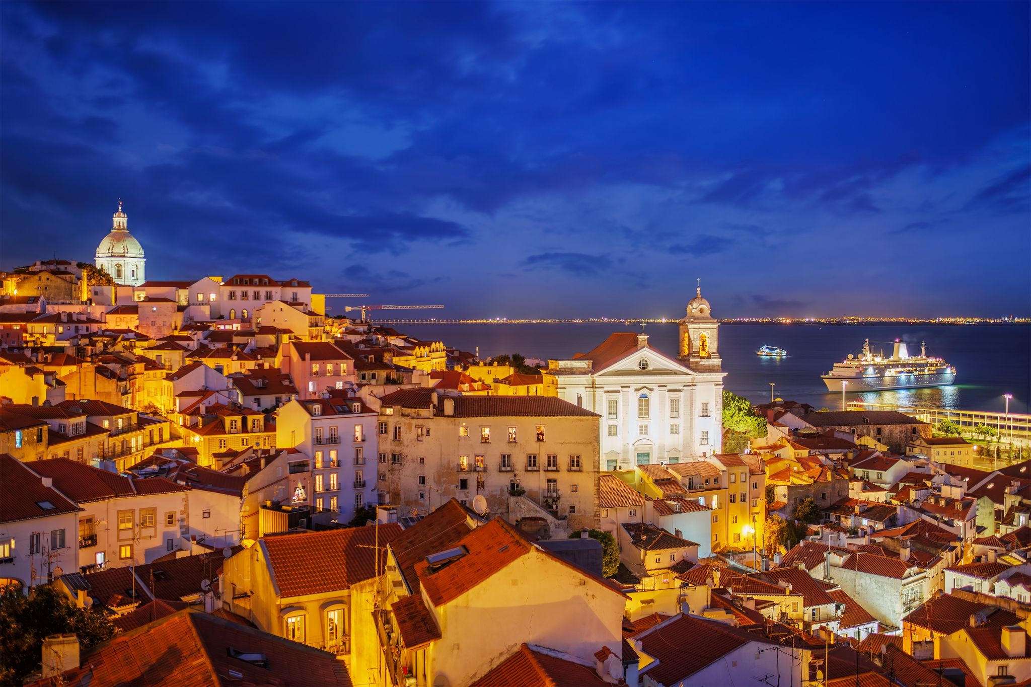 Photo of view of Lisbon famous view at night from Miradouro de Santa Luzia tourist viewpoint over Alfama old city district at night with cruise liner. Lisbon, Portugal.