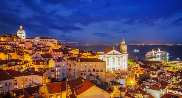 Photo of view of Lisbon famous view at night from Miradouro de Santa Luzia tourist viewpoint over Alfama old city district at night with cruise liner. Lisbon, Portugal.